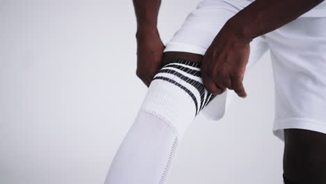 african-football-player-is-pulling-knee-sock-closeup-view-wearing-professional-sport-uniform